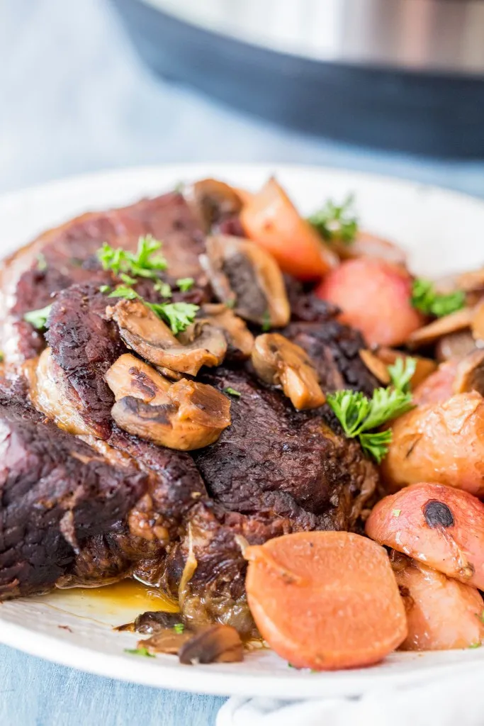 instant pot pot roast with radishes on a white plate