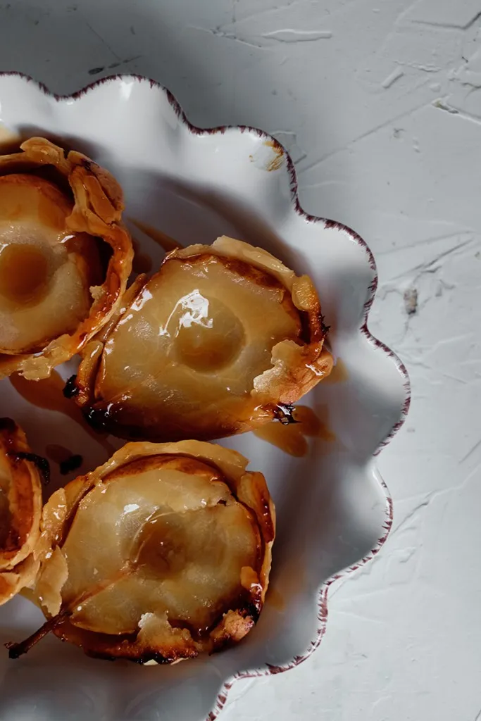 pear tarts face up with caramel sauce drizzled on top in a white casserole tart dish
