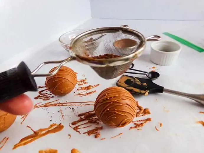 hot cocoa bombs with chocolate drizzle and cocoa powder on top