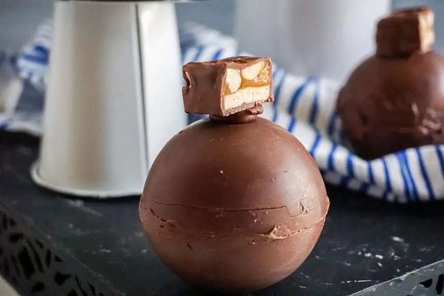 snickers hot cocoa bombs on a black table and white and blue napkin
