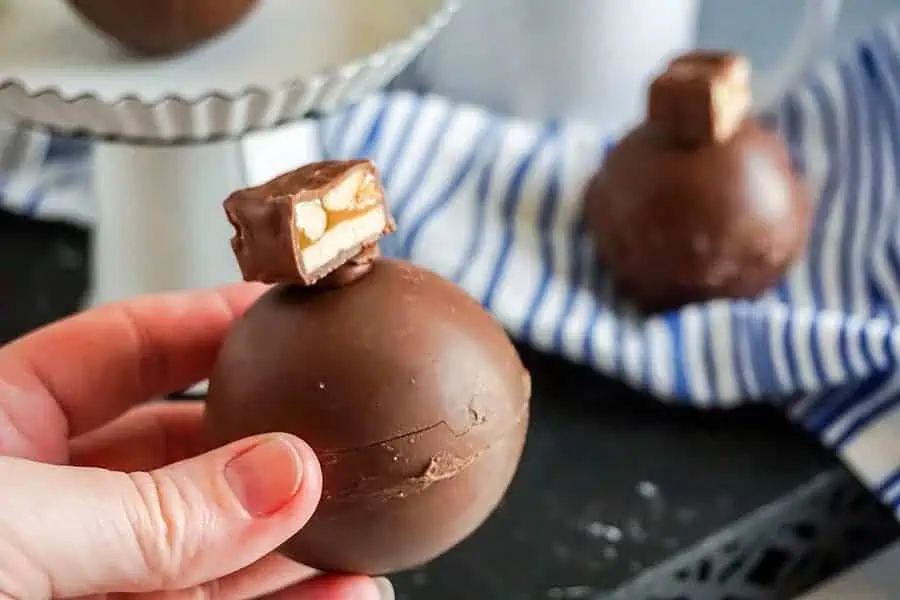 snickers hot cocoa bombs in a persons hand with a close up view