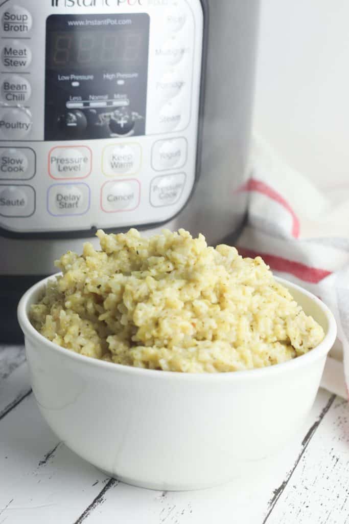 bowl of cheesy broccoli rice in front of instant pot kitchen utensil
