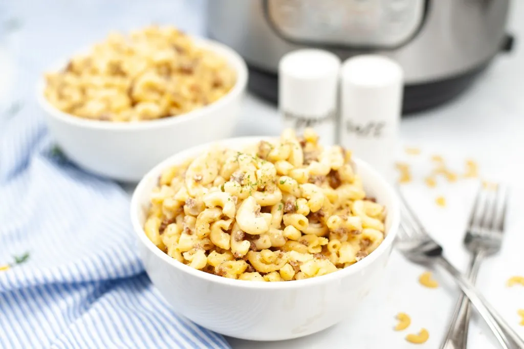 hamburger helper in white bowls with instant pot in background