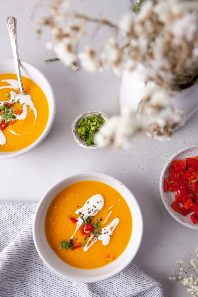 Instant Pot butternut squash soup garnished with sautรฉed red peppers and sour cream