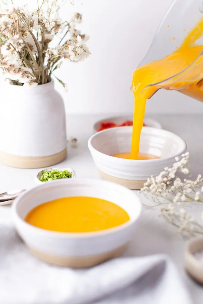 Pouring the instant pot butternut squash soup into white bowls