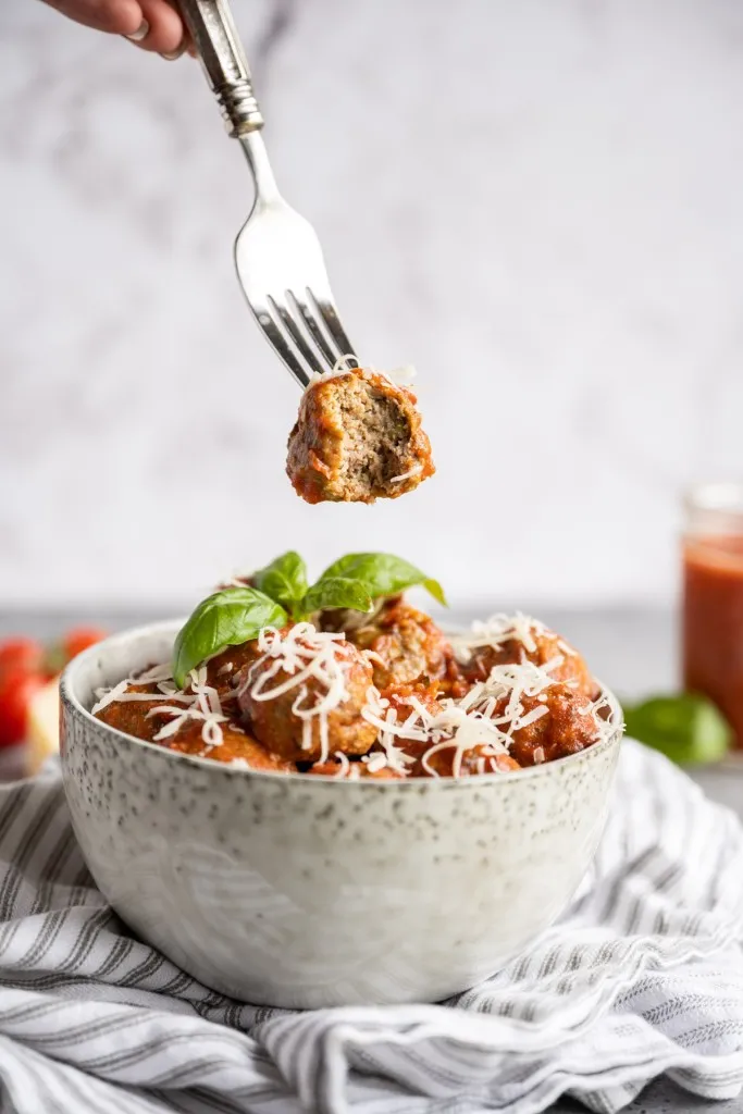 baked keto meatballs with fresh basil in a bowl and fork