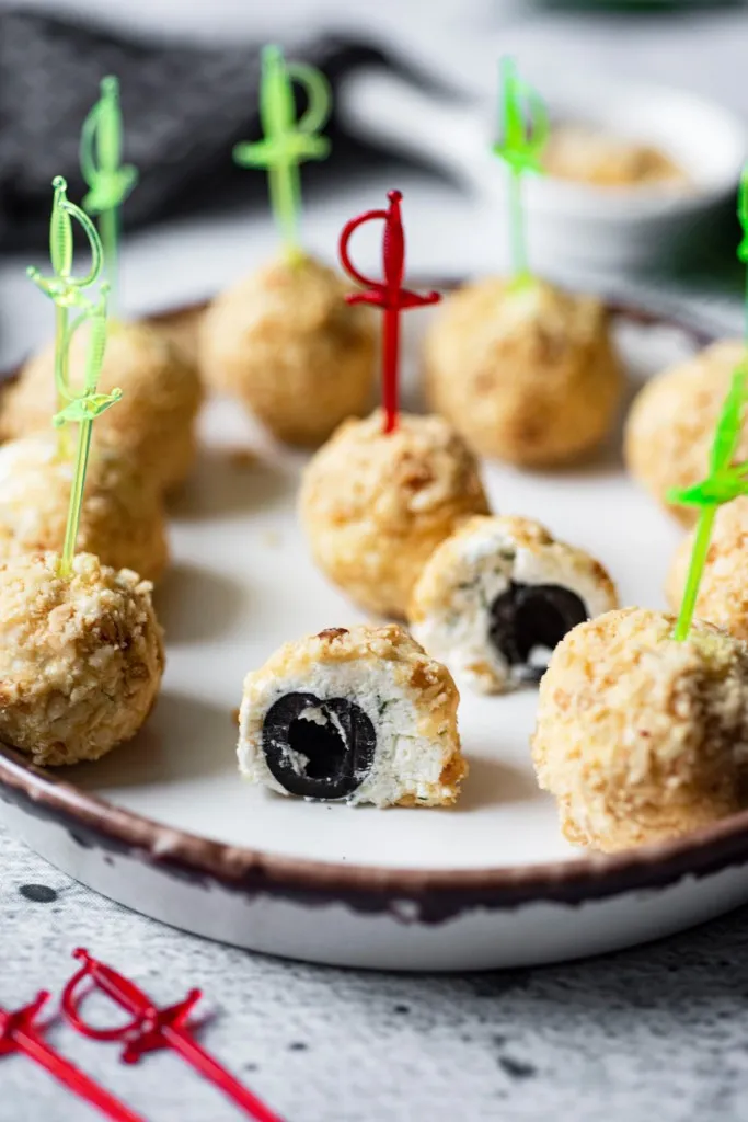 side shot of feta cheese covered olives cut in half on a stone plate