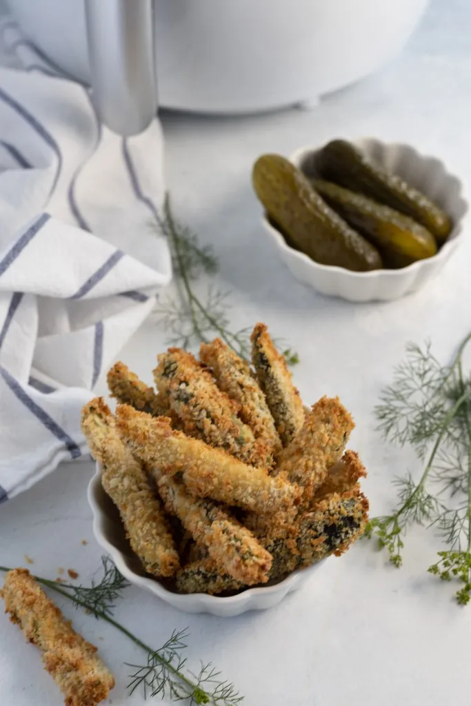 air fried pickles in a white bowl with fresh dill