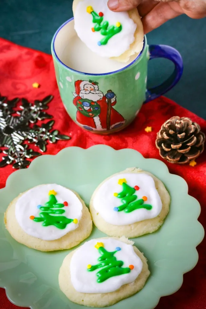 christmas cookies on a green plate with a red cloth and coffee cup