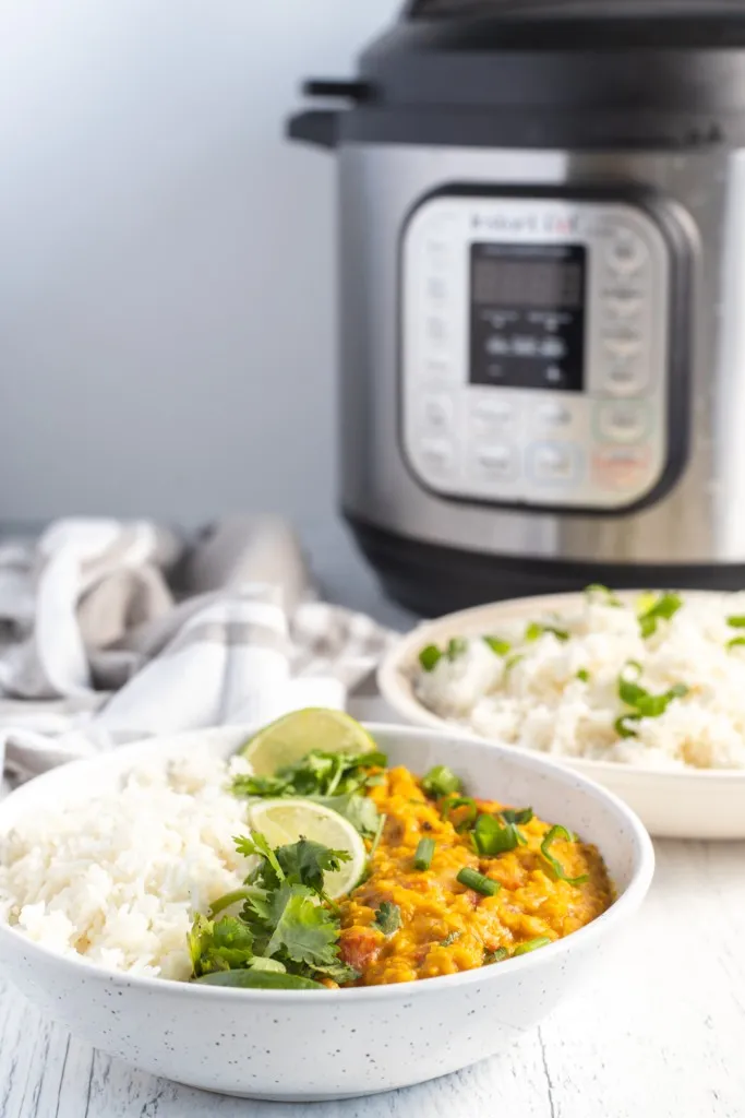 a bowl of lentil curry in front of an instant pot