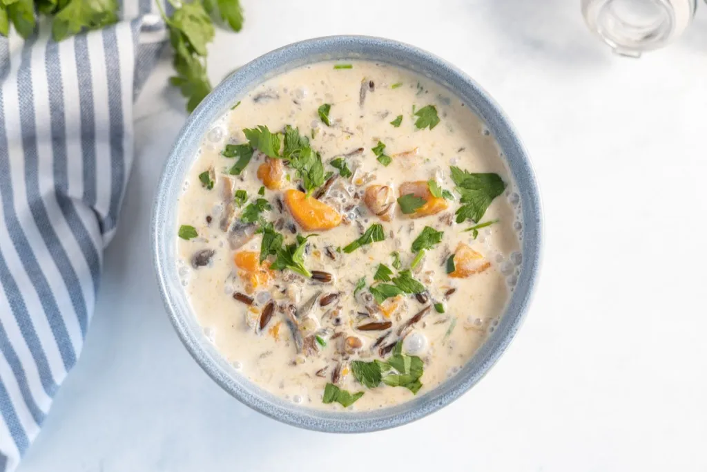 wild rice and mushroom soup in a blue bowl with a white and blue napkin