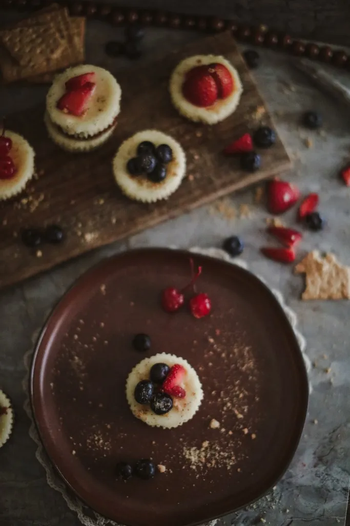 blueberries and strawberries on a cheesecake on a brown plate