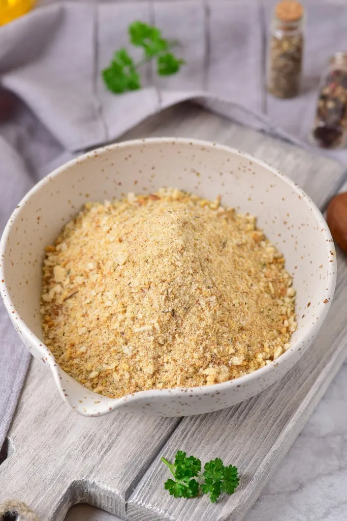 main image of a bowl of air fryer breadcrumbs in a speckled bowl on a white washed cutting board