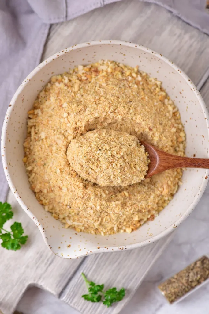 image of a bowl of air fryer breadcrumbs in a speckled bowl on a white washed cutting board