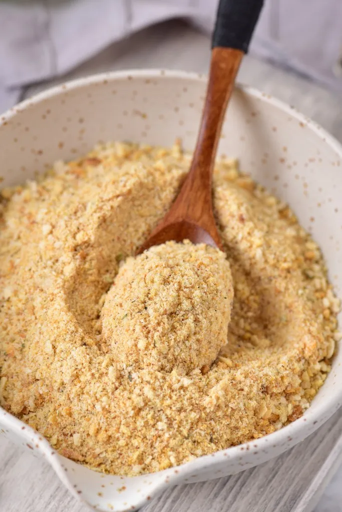 a vertical overhead shot of breadcrumbs on a wooden spoon