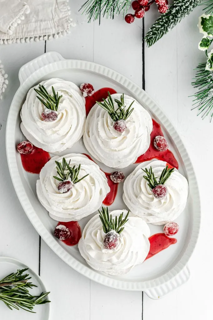 overhead shot of Christmas Pavlovas on a white plate and rosemary cranberry curd drizzled around