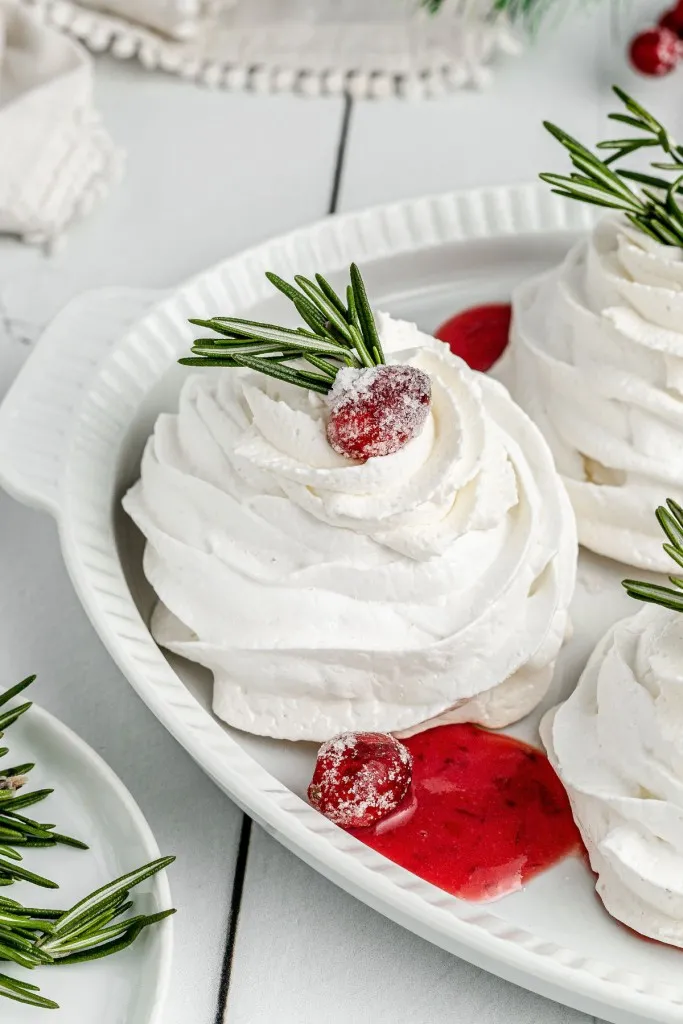 white delicate pavlova with sugared cranberries and cranberry curd