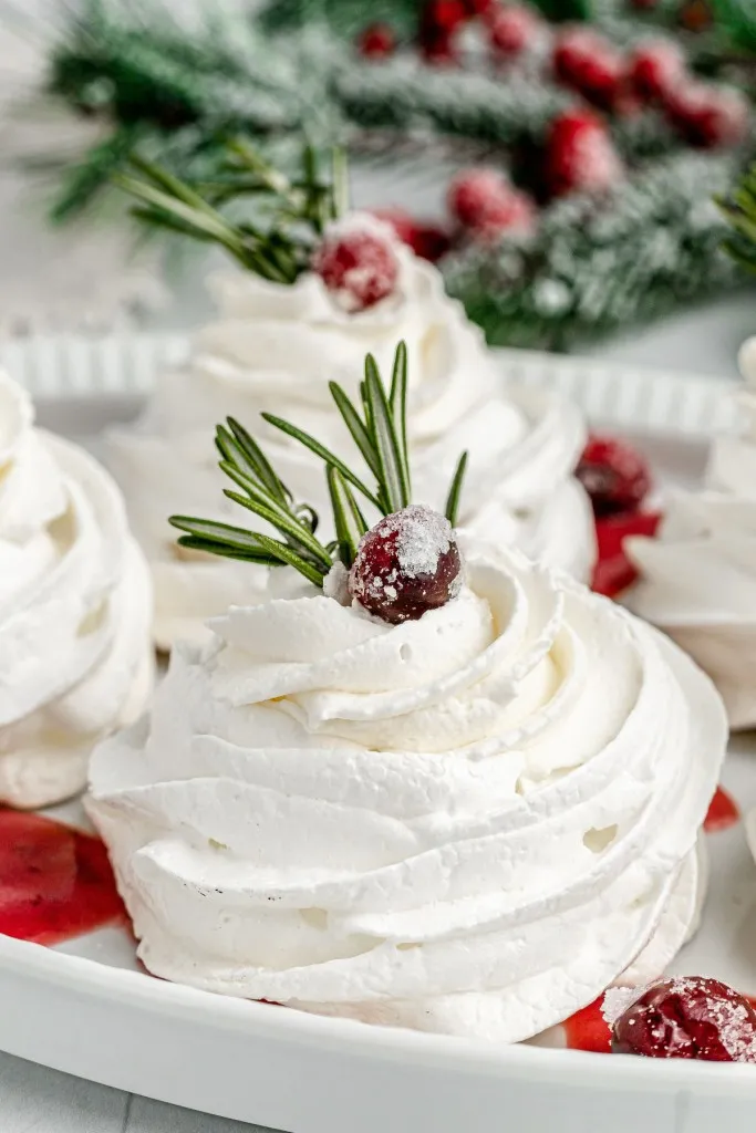 sugared cranberry and fresh rosemary on top of a christmas pavlova filled with rosemary infused cranberry curd