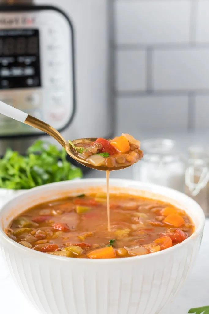 instant pot lentil soup on a spoon in a white bowl
