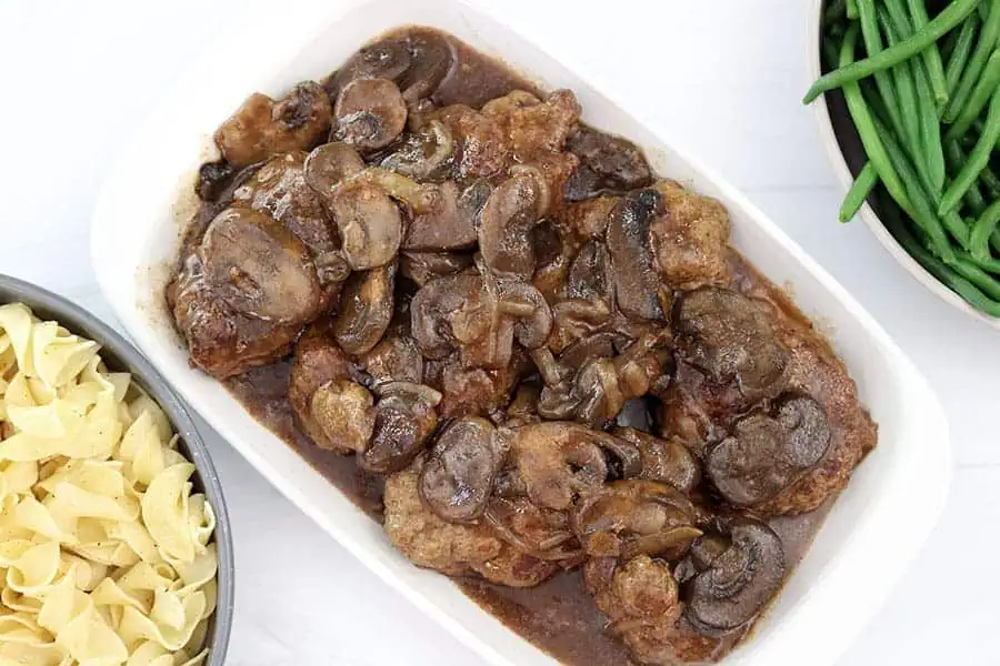slow cooker salisbury steak with mushrooms on a white dish