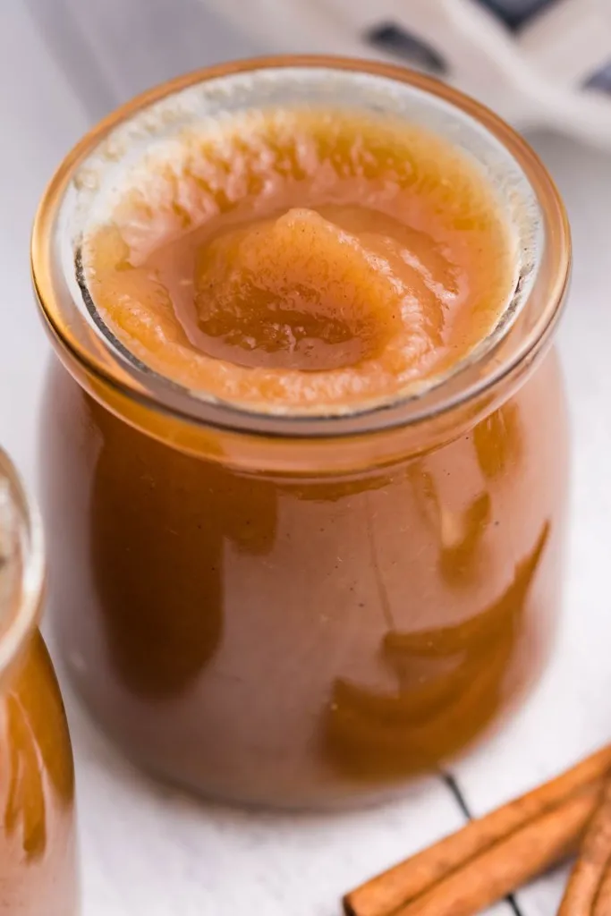 fresh homemade apple butter with cinnamon sticks on background