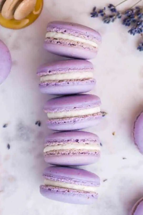 Lavender macarons with pretty feet stacked on a white marble counter