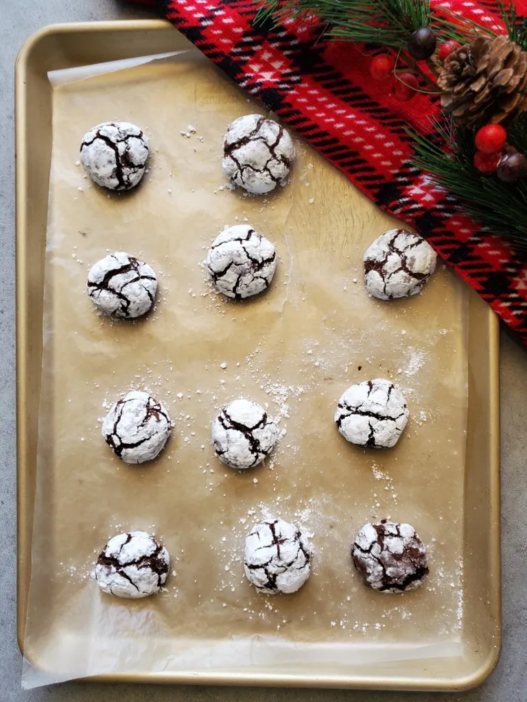 the easiest chocolate crinkles cookie recipes for christmas on a cookie sheet with parchment paper