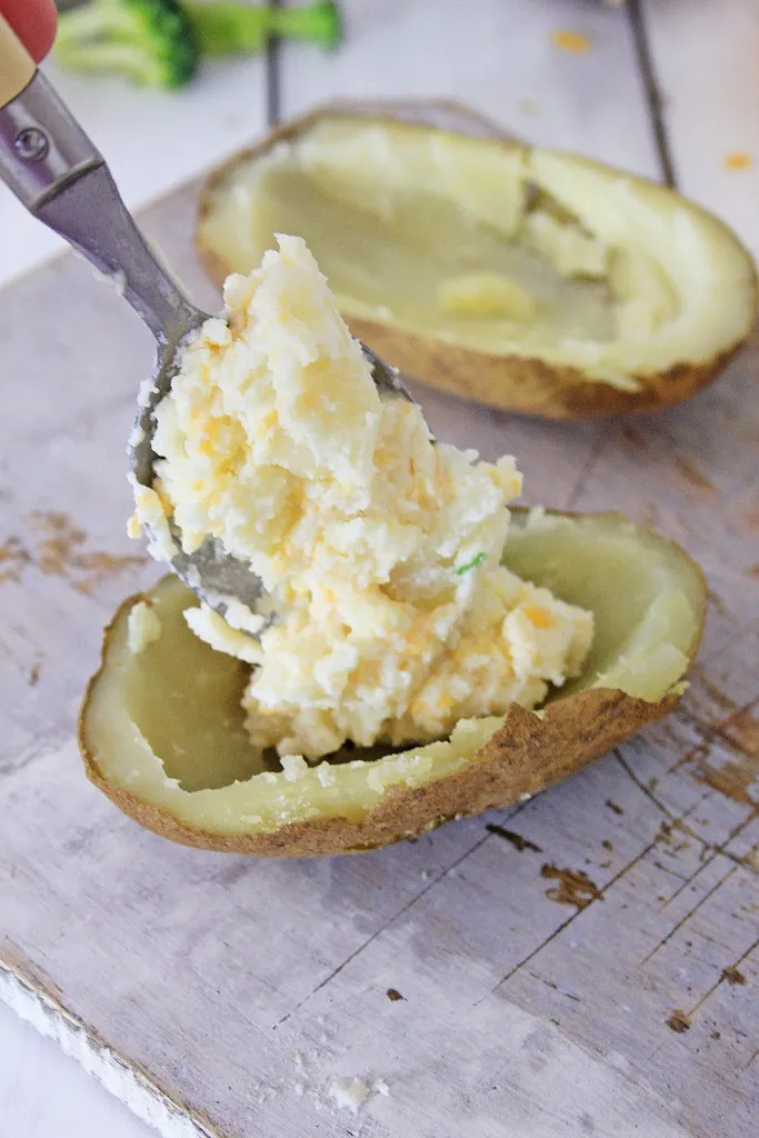 mixture of stuffed baked being returned to potato half