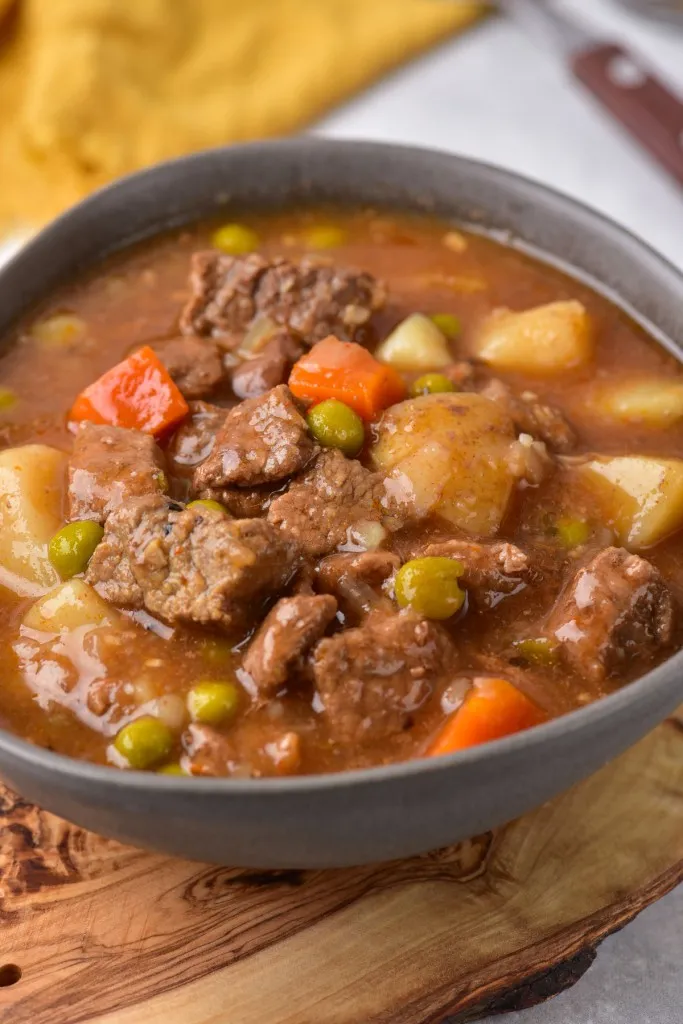 a bowl of instant pot beef stew with chunks of potatoes, carrots, and peas.