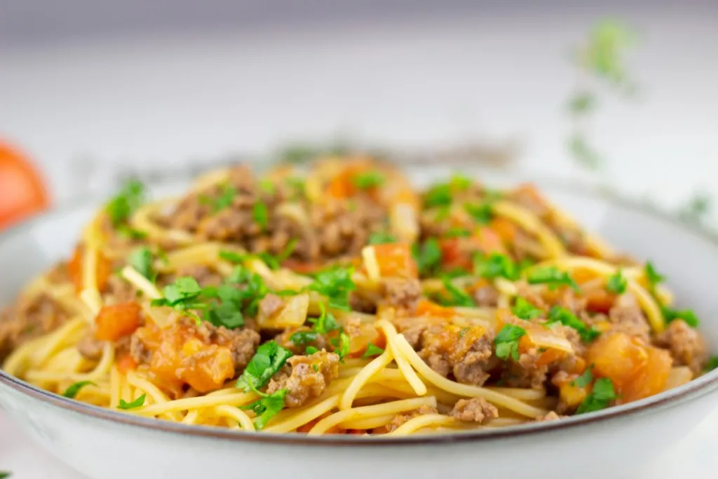 close up view a brown rimmed ceramic plate with spaghetti taco served on top