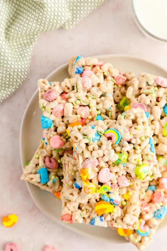 marshmallow lucky charms bars stacked on top of a peach colored plate