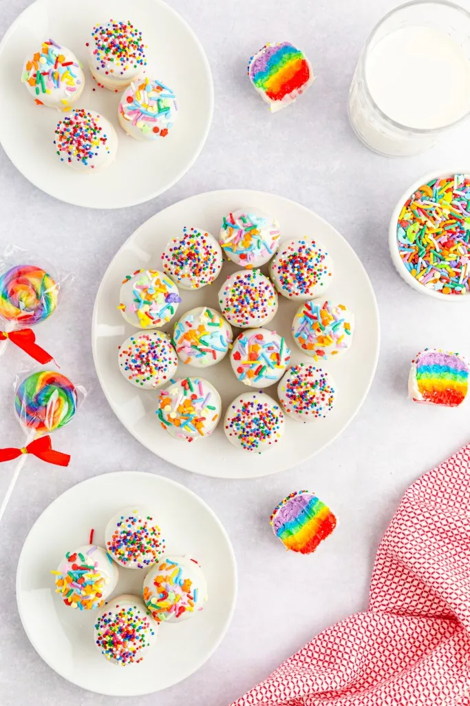rainbow lollipops with cake mix balls with a rainbow center that are covered in white chocolate colorful sprinkles
