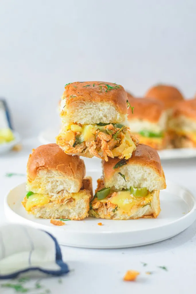 best stack of buffalo chicken sliders stacked on a each other in a pyramid on a white creamic lipped plate.