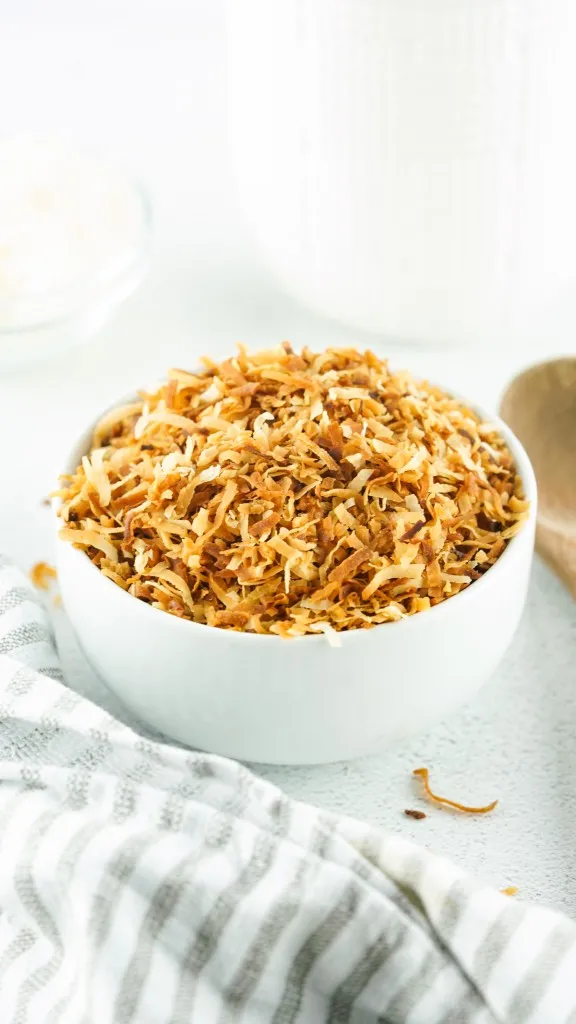 a mound of how to toast coconut in a white bowl