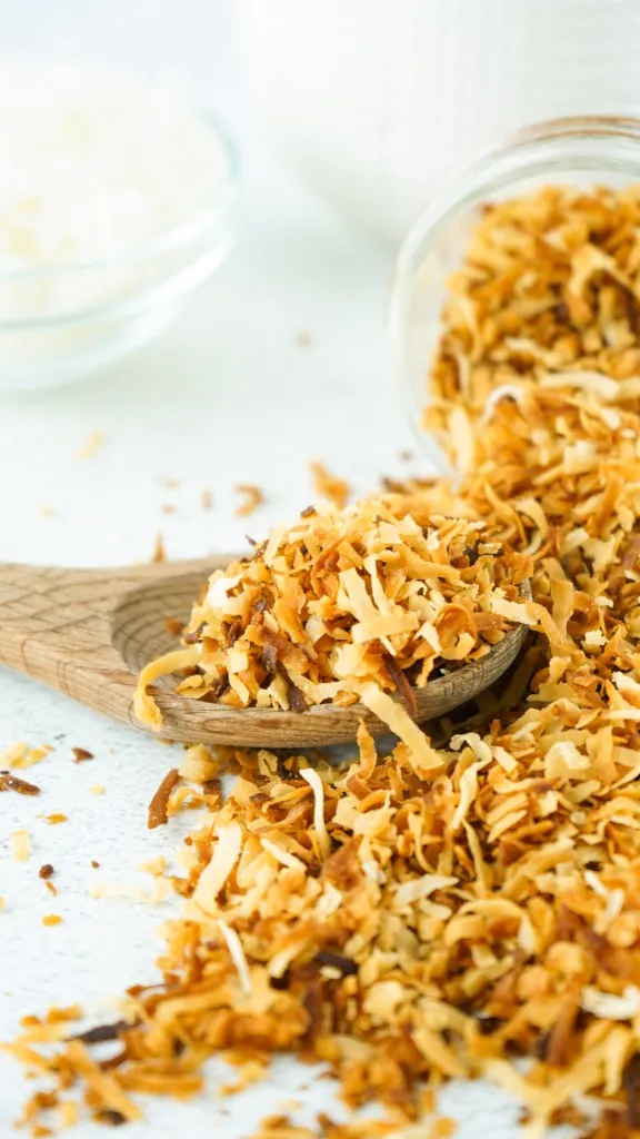 toasted coconut spilled out of jar and on a wooden spoon