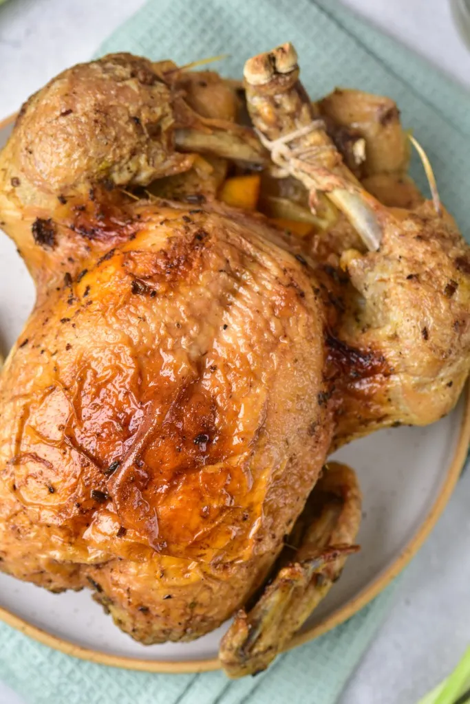 overhead view of brown skin of instant pot made chicken recipe on a white ceramic plate with gold trim