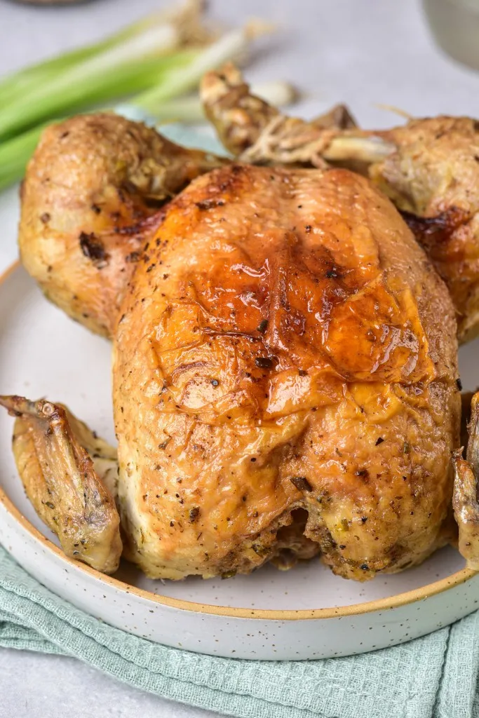 side view of whole chicken made in the Instant Pot on a white speckled ceramic plate