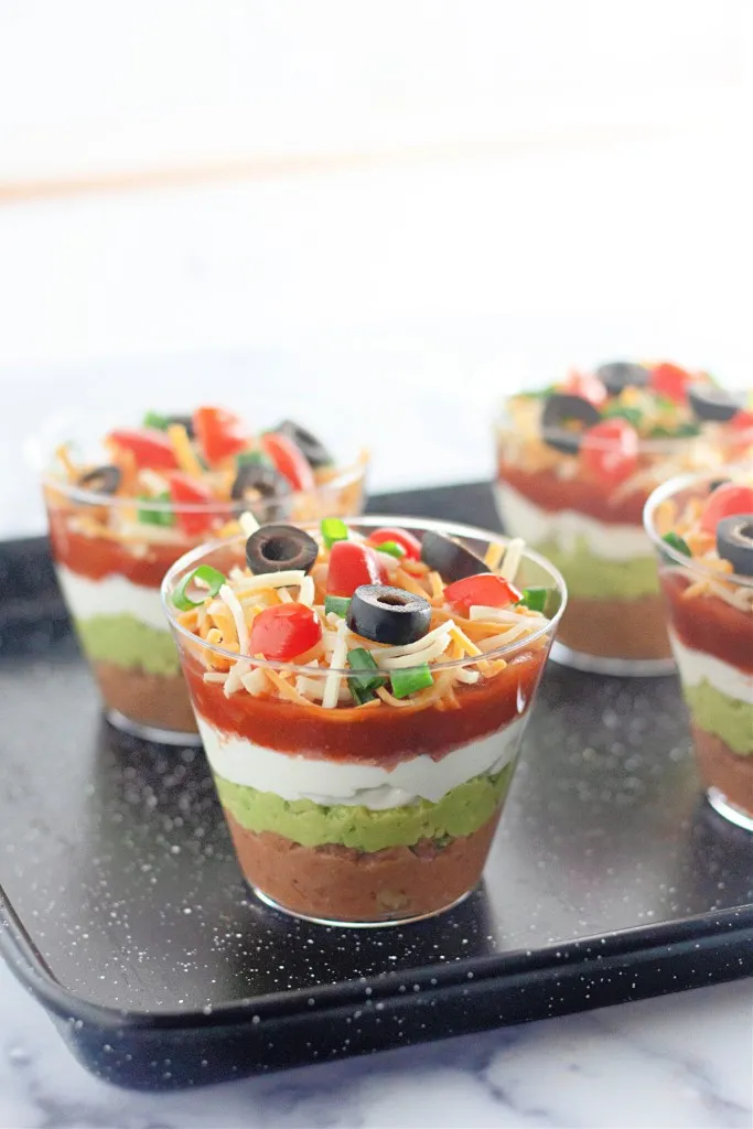 Assembled 7 Layer Dip Cups on a black serving tray.