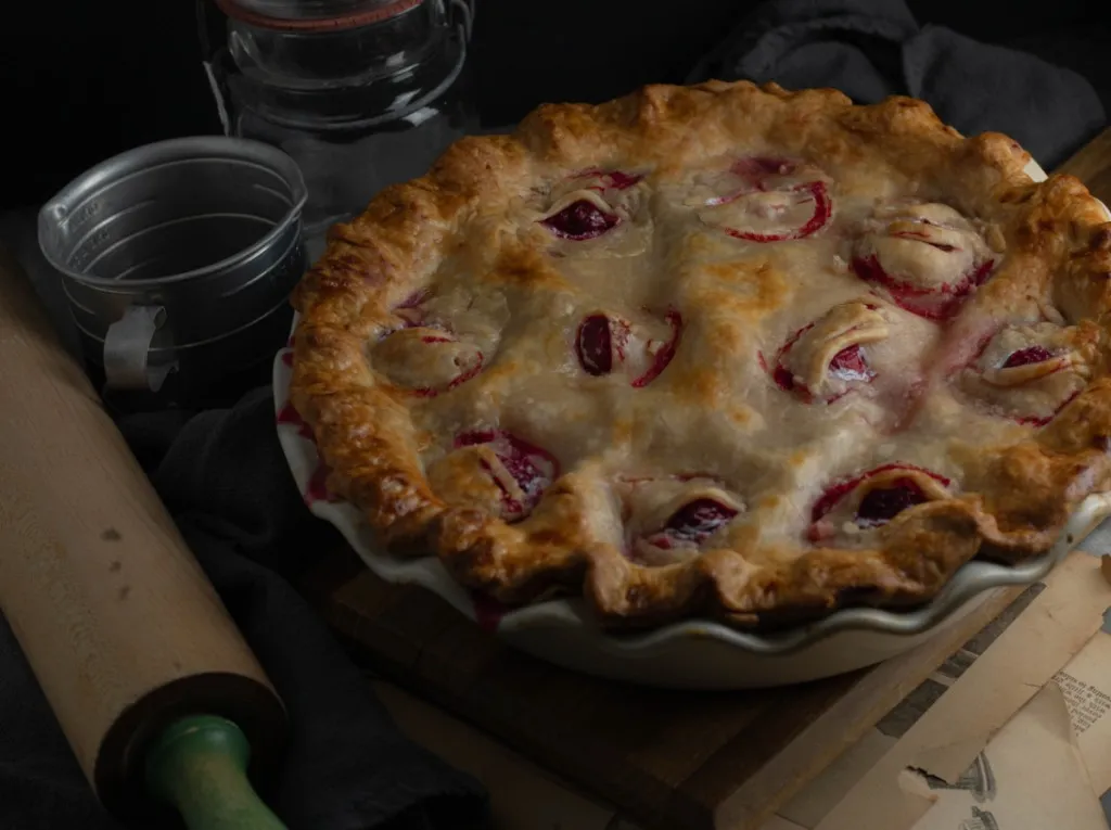 Freshly baked Eyeball Pie with wooden rolling pin, on a dark countertop.