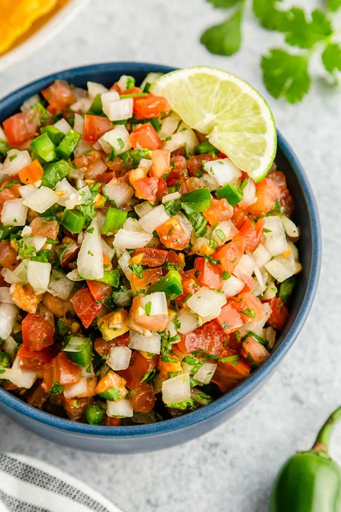 Bowl of Pico De Gallow, striped cloth, bowl of tortilla chips.