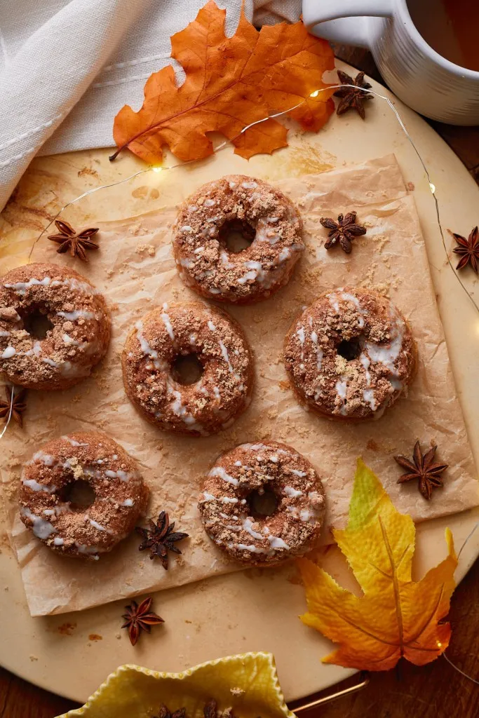 Overhead view of cinnamon roll donuts on a wooden board with fall-inspired decorations.