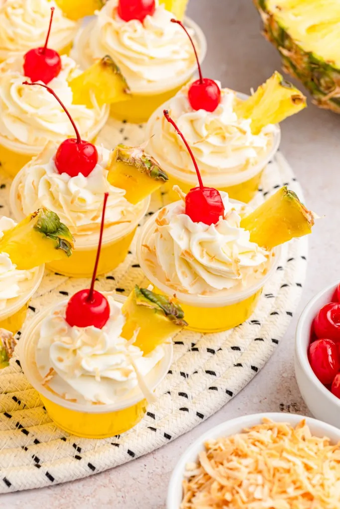 Pina colada jello shots on a decorative mat, recipe ingredients on the countertop.