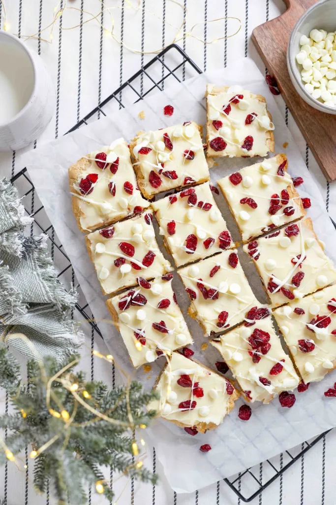 Overhead view of cranberry bliss bars on parchment paper on a wire cooling rack.