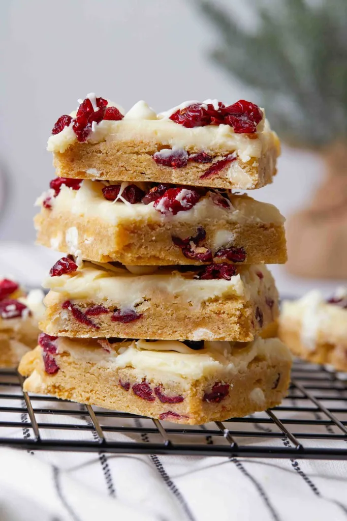 Stacked cranberry bliss bars on a wire cooling rack.