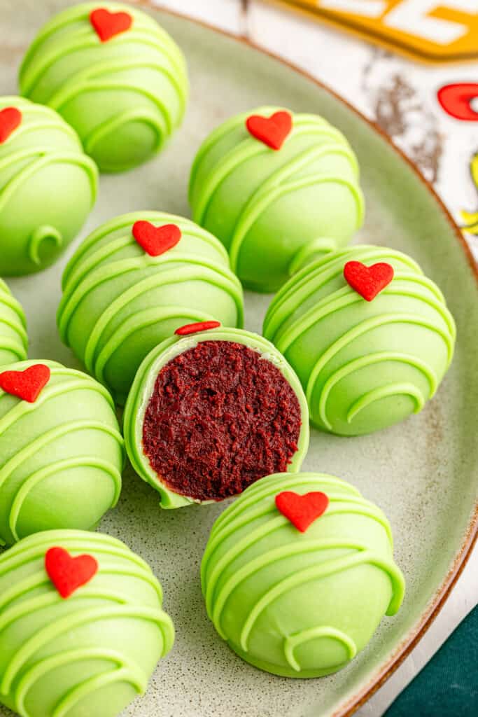 Platter of Grinch Oreo balls, one ball with a bite removed.