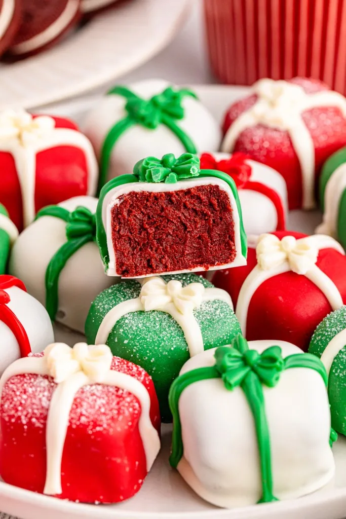 Close up of Christmas Oreo presents on a white plate, a bite removed from one of the presents.