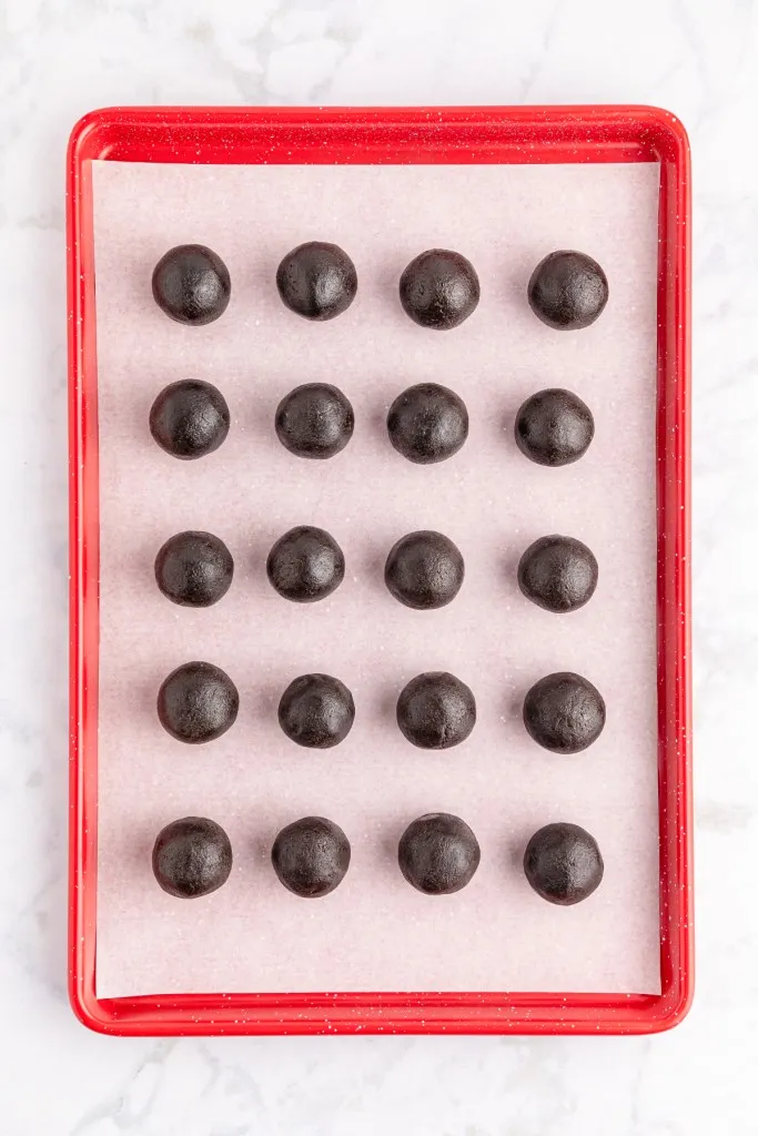 Baking tray lined with parchment paper with smooth Oreo balls.