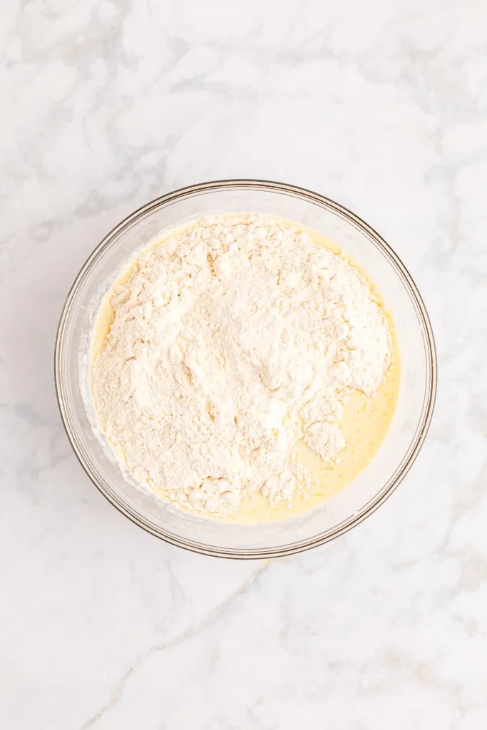 Mixing bowl with wet and dry ingredients on a marble countertop.