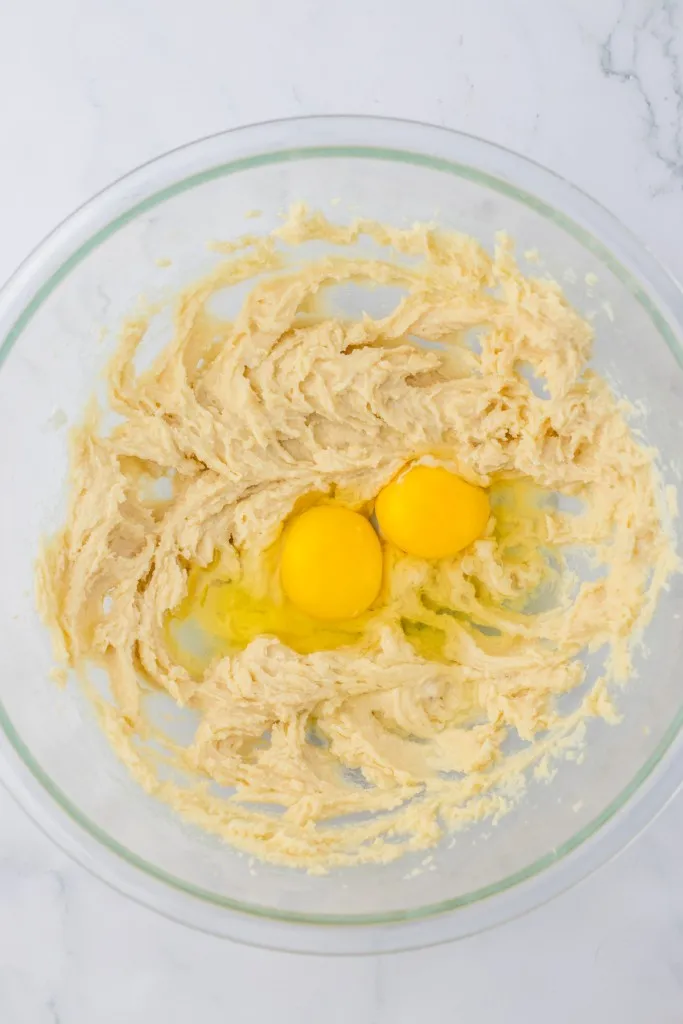 Mixing bowl with creamed butter and sugar mixture, and eggs.