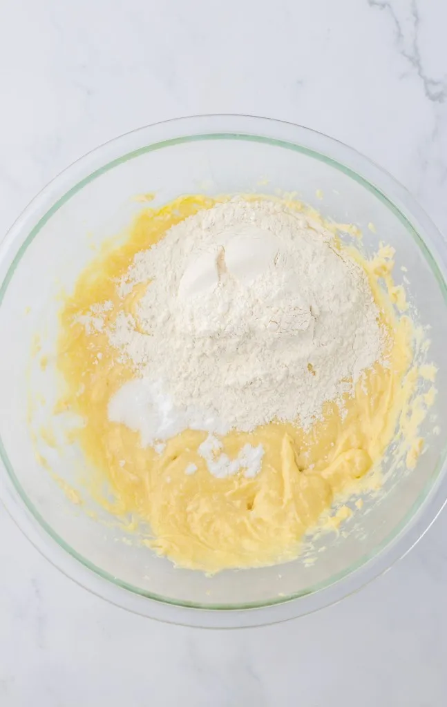 Mixing bowl with wet cookie dough batter, flour, baking soda, and salt.